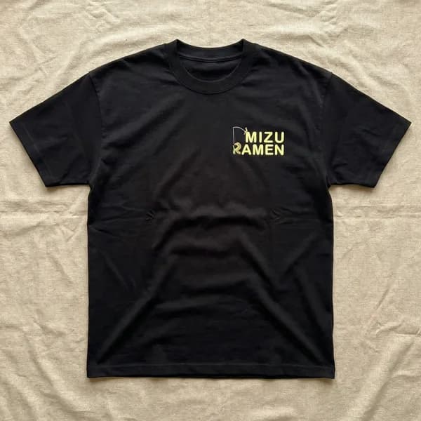胸元に黄色のロゴをプリントした黒いTシャツの平置き