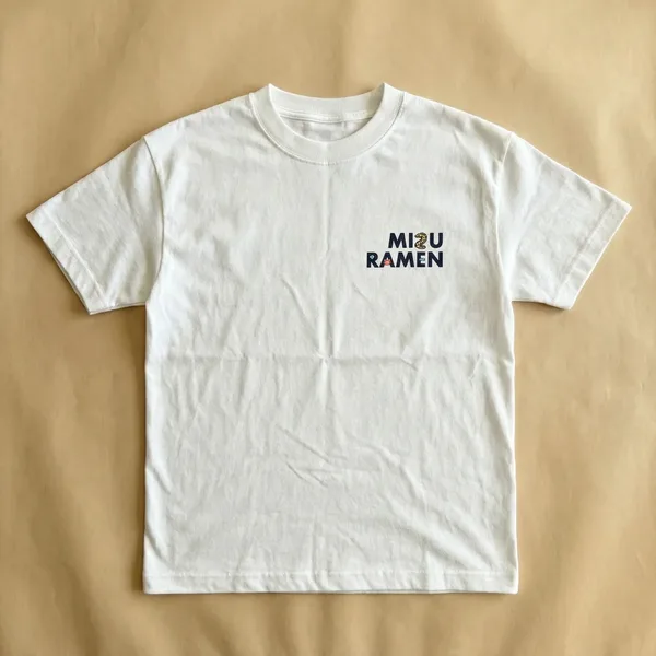 胸元にロゴを入れた白いTシャツを着て街中に立つ人物